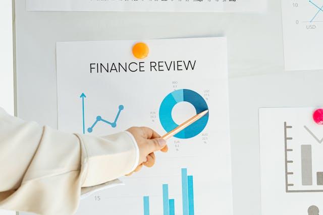 hand-pointing-to-a-financial-review-document-showing-different-graphs