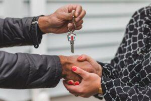 two people shaking hands as they hand over house keys